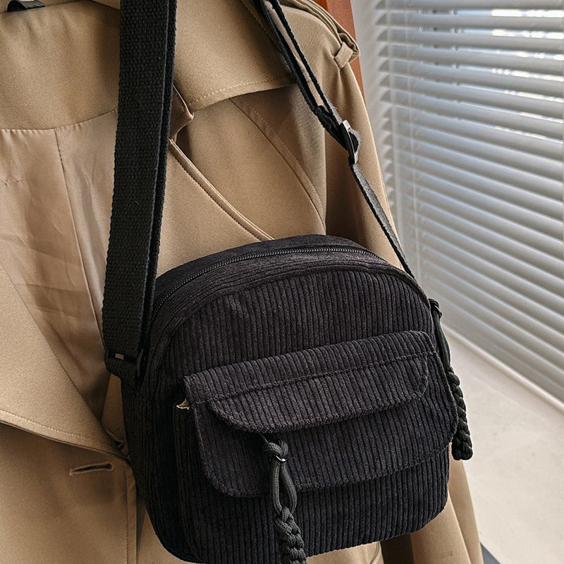 Black small shoulder bag for women, with a functional front zip pocket and adjustable strap.