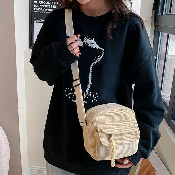 Chic beige small crossbody bag for women, ideal for essentials with its front zip pocket.