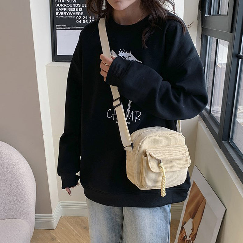 Beige small shoulder bag for women, with a functional front zip pocket and adjustable strap.