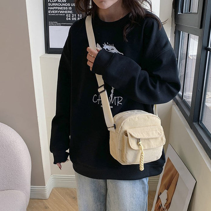 Beige small shoulder bag for women, with a functional front zip pocket and adjustable strap.