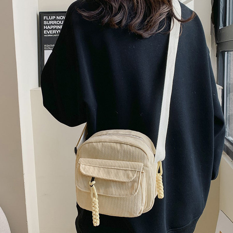 Stylish beige women's small bag, crossbody design, with an accessible front zip pocket.