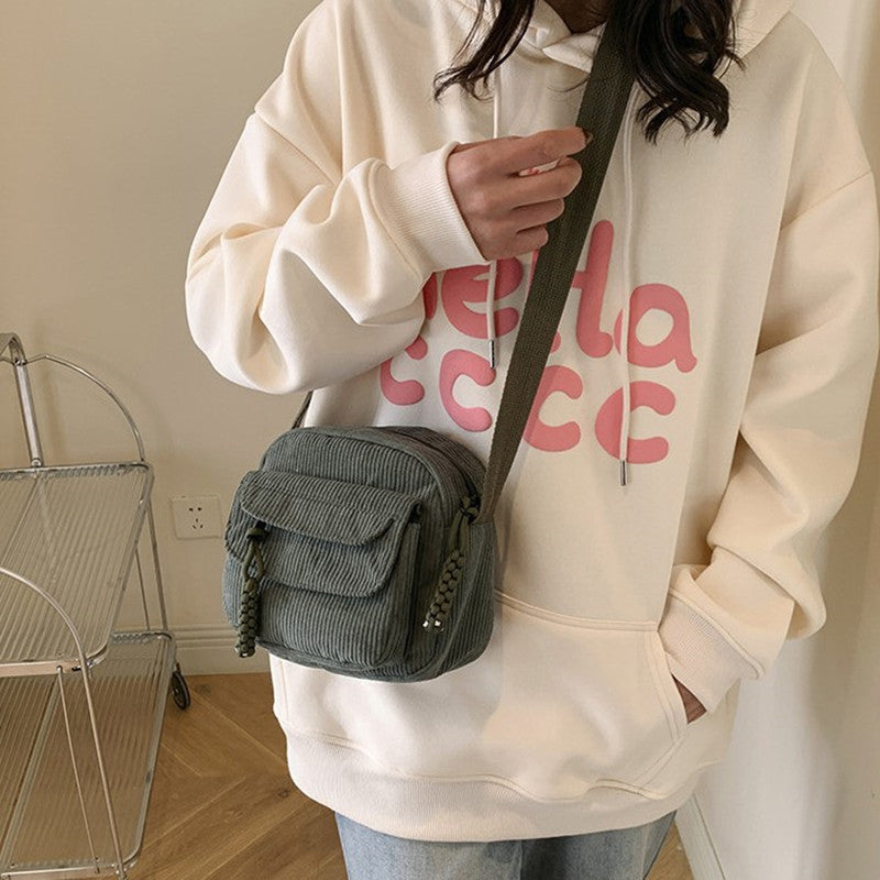 Compact green daily essential women's crossbody bag with a secure front zip pocket.