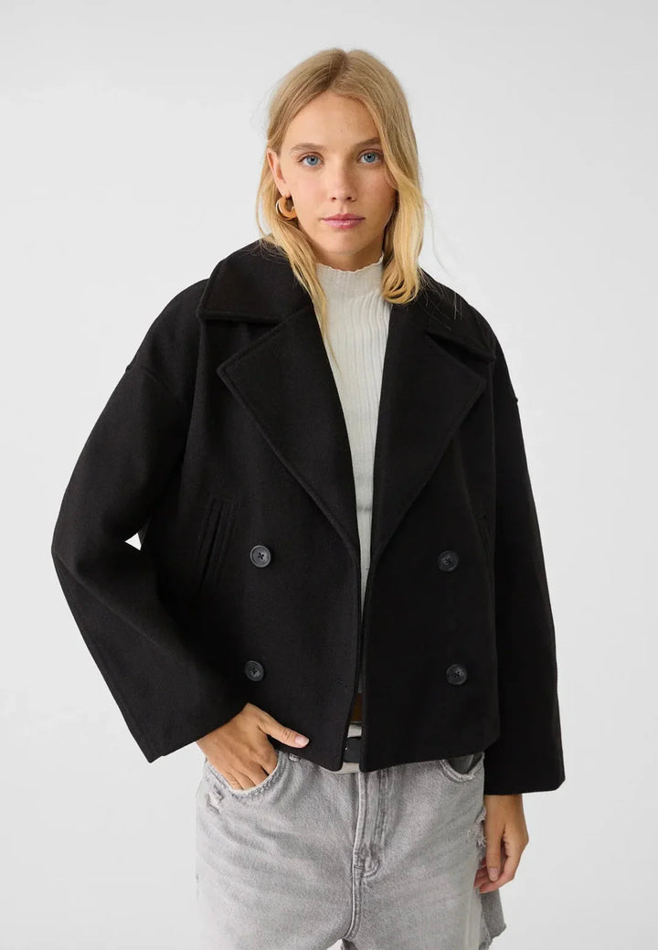 Modern women's short coat with double-breasted front. Stylish cropped jacket, ideal for versatile fashion.