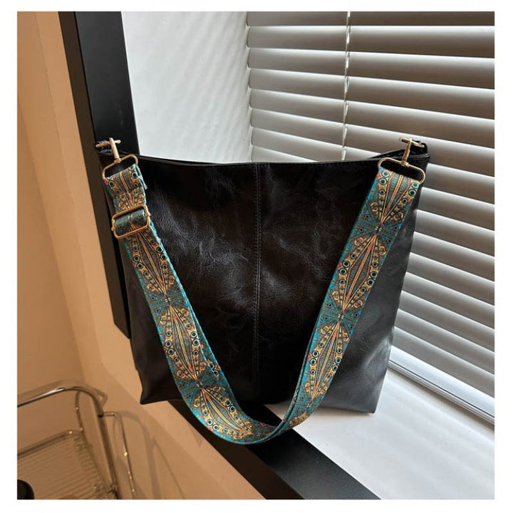 Detailed view of the women's faux leather shoulder bag, highlighting its structure and fashionable embellished strap.