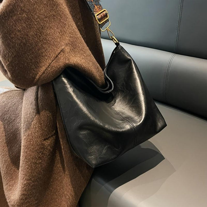 Classic black faux leather women's shoulder bag, featuring a chic embellished strap. A versatile fashion handbag.