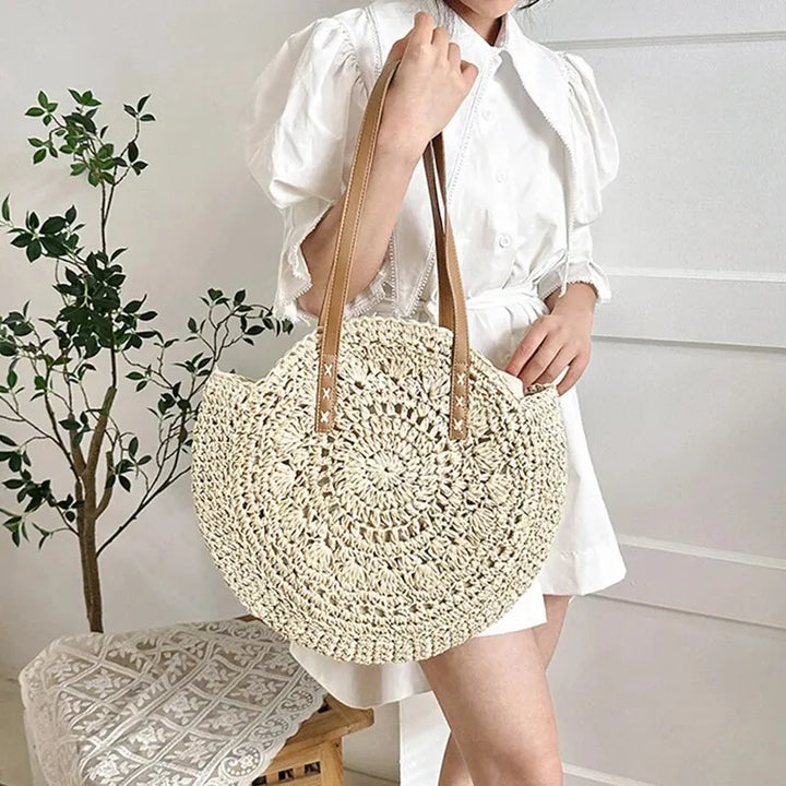 Natural straw round woven beach tote bag for women. Stylish summer shoulder bag, ideal for vacation.