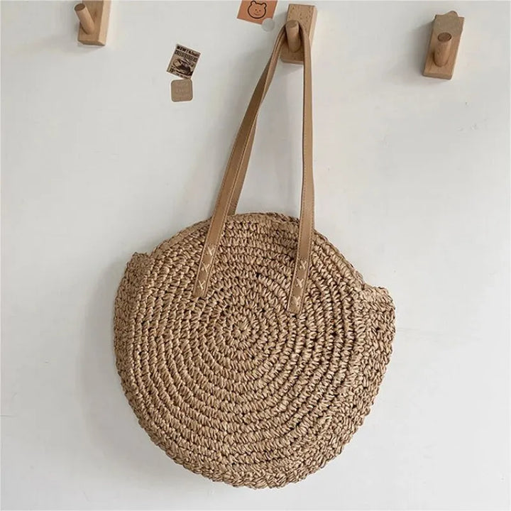 Round woven straw beach tote bag for women. Natural summer shoulder bag, ideal for resort and vacation.
