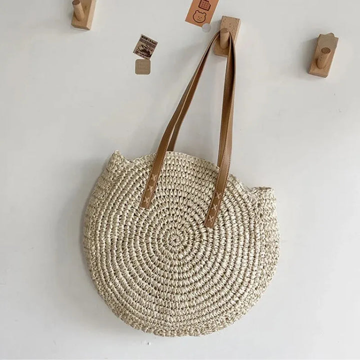 Women's natural round woven beach bag, a chic summer tote. Perfect for carrying essentials on vacation.