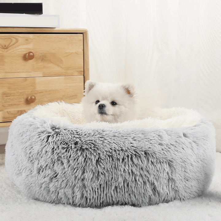 "Cozy plush donut dog bed with deep sides, faux fur, circular shape for comfort and anxiety relief in various sizes."