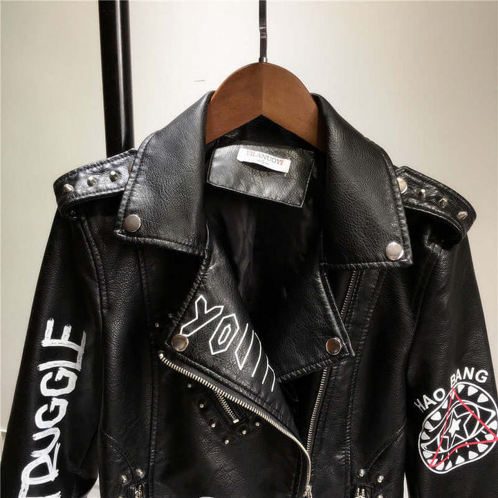 Fashionable women's edgy black PU leather jacket with prominent rivet detailing, a classic biker/moto style.