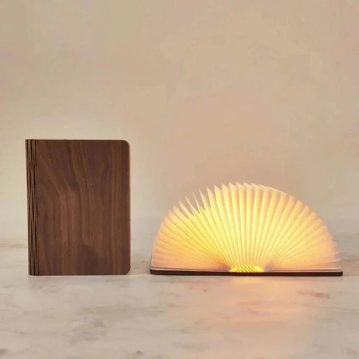 "Elegant foldable LED book lamp, warm white light, 360-degree design, portable for home or travel, wood and paper material."