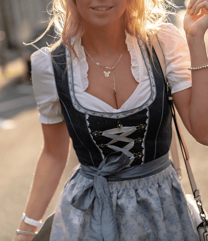 Traditional Women's Dirndl midi dress outfit. Elegant Bavarian set includes azure dress, white blouse, and decorative apron.