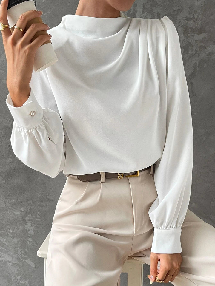 Woman in a loose fit bishop sleeve blouse. Elegant long sleeve top for sophisticated business casual or evening fashion.