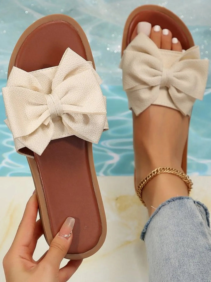 Elegant women's flat slide sandals with decorative bow, perfect for summer casual wear & vacation. Comfortable slip-on design.