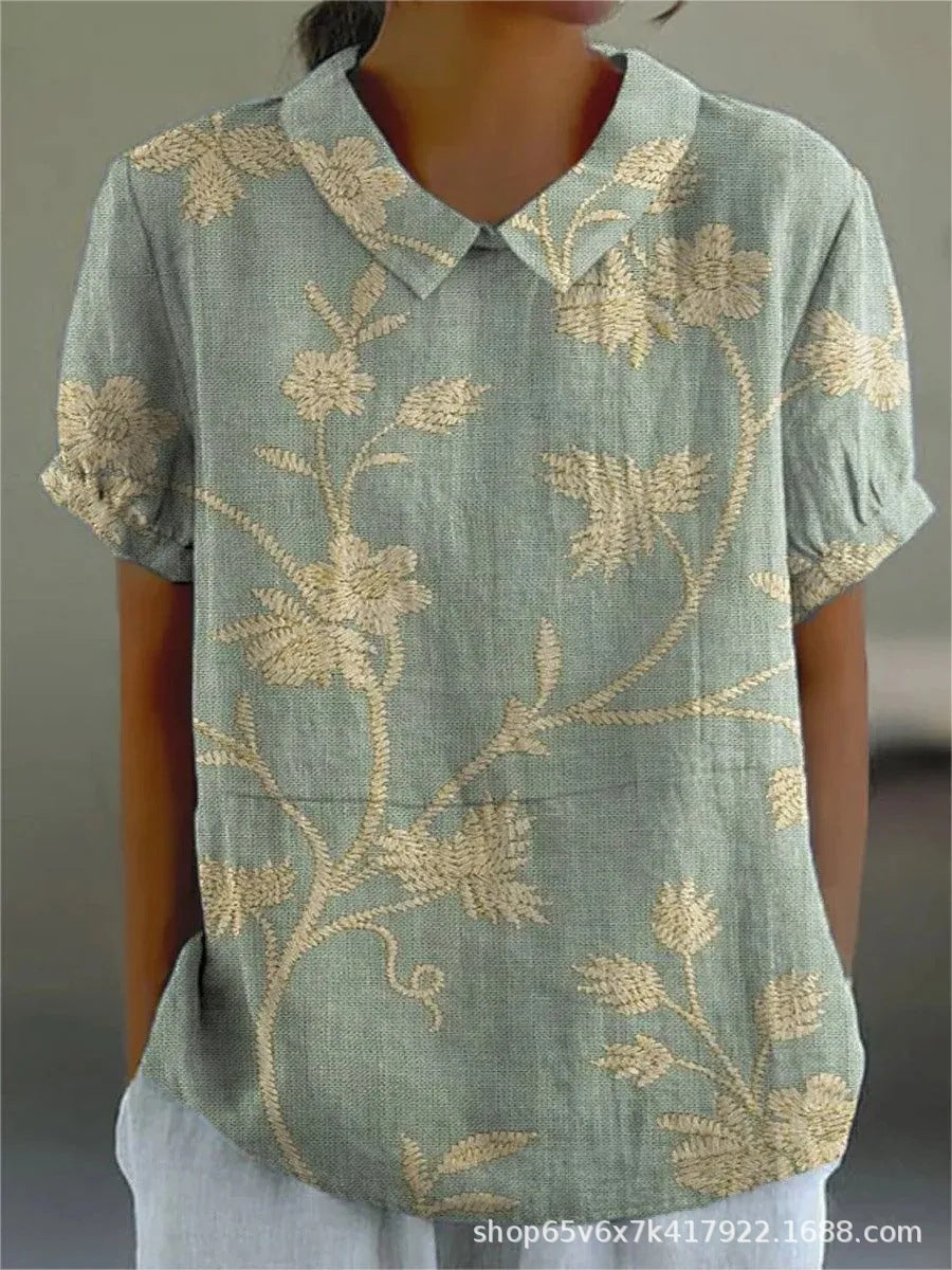 Elegant women's top featuring a beautiful floral pattern, short sleeves, and a classic Peter Pan collar.