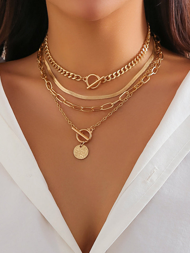 Women's gold layered necklace set featuring delicate chains & various pendants, including a chic coin design.