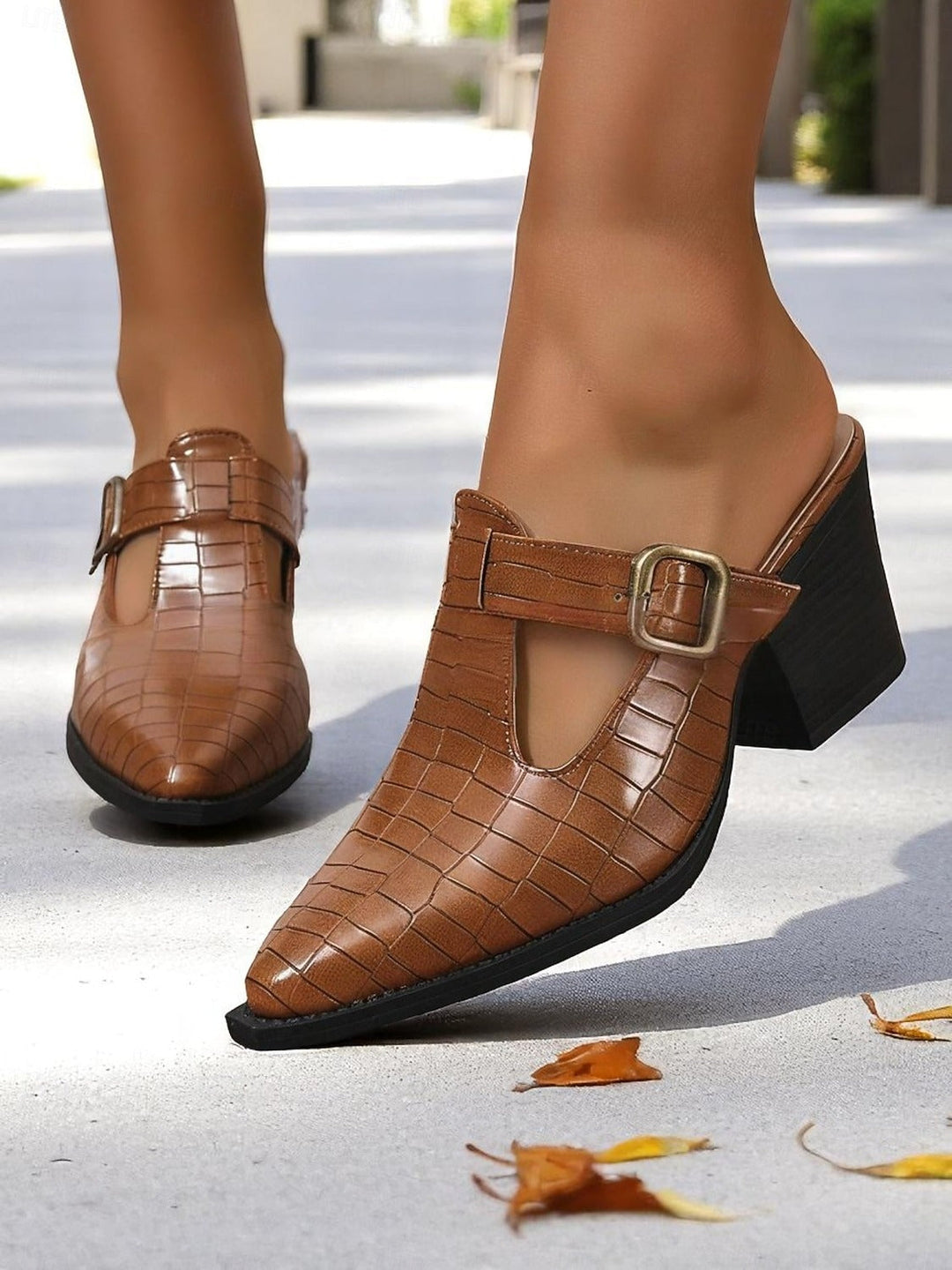 Close-up of women's slip-on mules featuring a stylish buckle and comfortable block heel, ideal for casual or dress wear.
