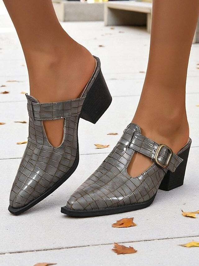 View of women's mules, highlighting the comfortable block heel and slip-on design with an elegant buckle detail.