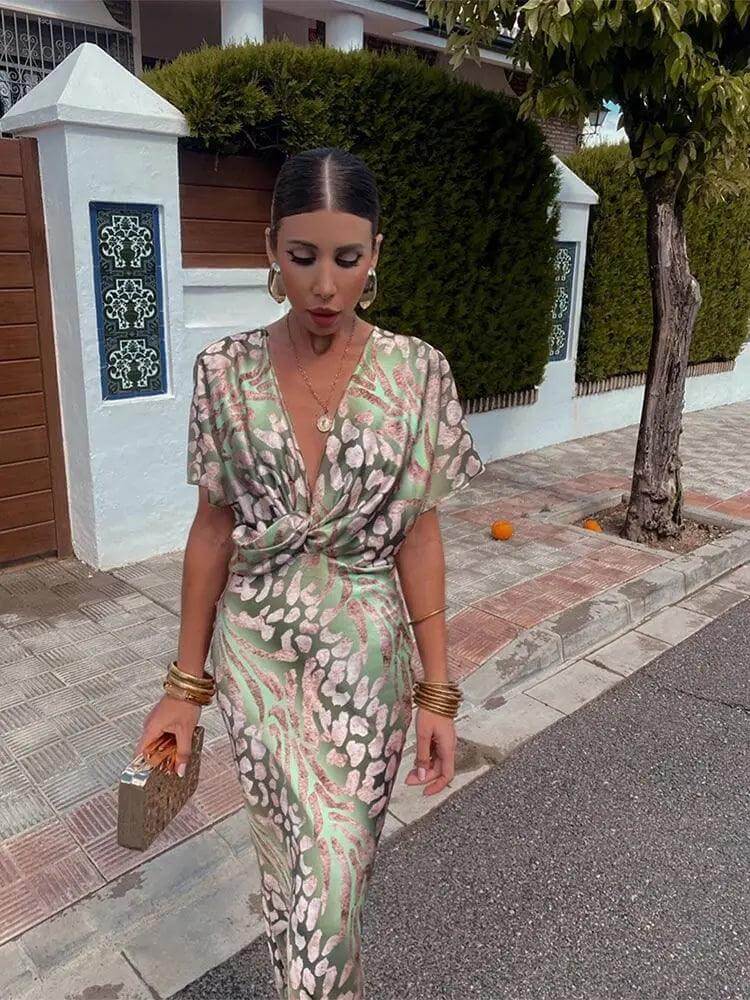 Stylish women's pleated midi dress in olive green satin with vibrant floral print, V-neck, and comfortable short sleeves.