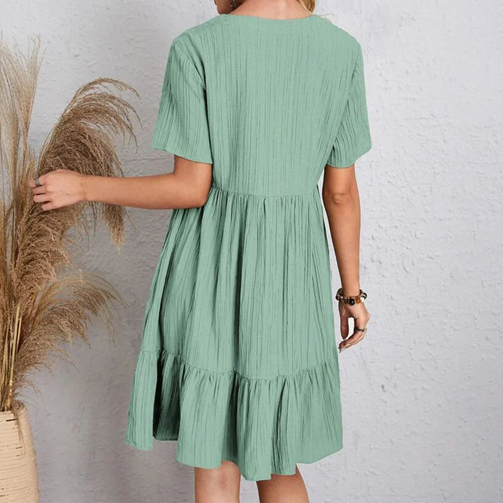 Elegant V-neck summer dress worn outdoors, a perfect flowy sundress for women's vacation fashion or beach trips.