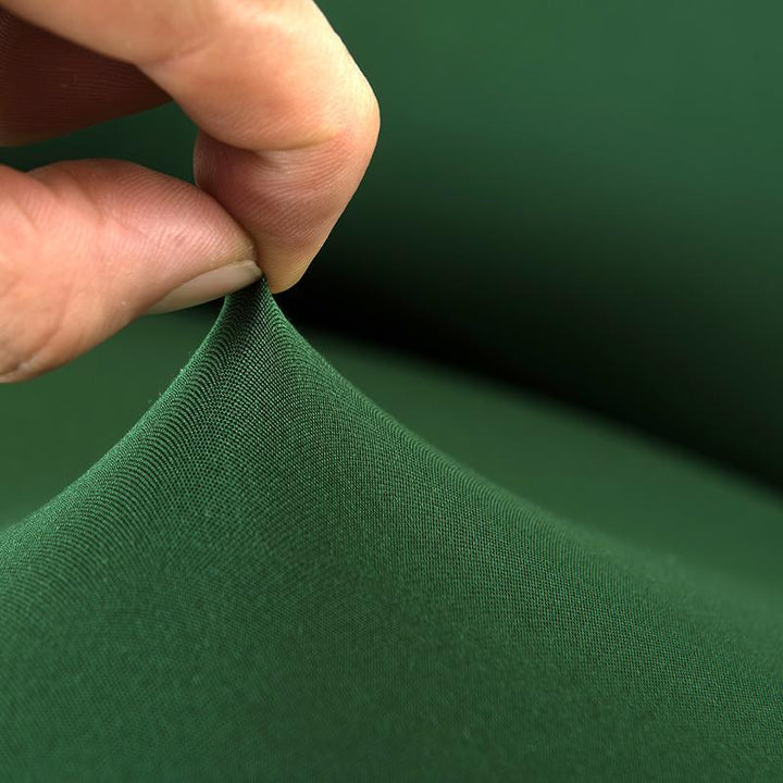 "Emerald green sofa cover on a couch, showcasing its stretchy and durable fabric, perfect for protection and style."