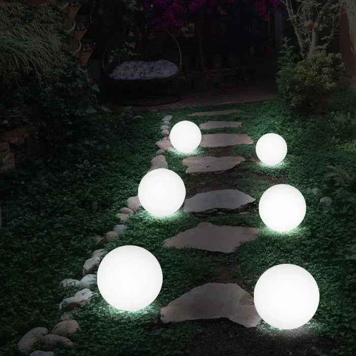 Multiple GlowSphere spherical garden lights creating a festive atmosphere in an outdoor setting.