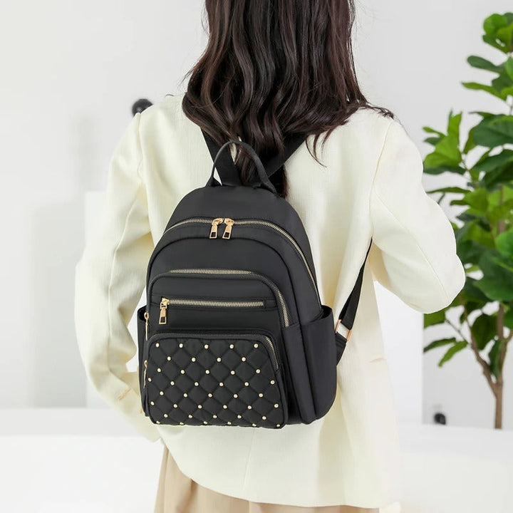 Side view of a khaki lightweight women's nylon backpack, with a convenient exterior pocket for water bottles.