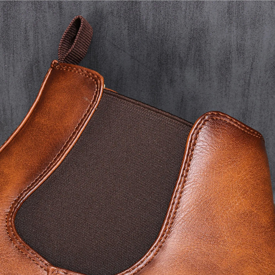 Side view of men's slip-on Chelsea ankle boots, showcasing elastic gussets and sleek profile. Versatile footwear.