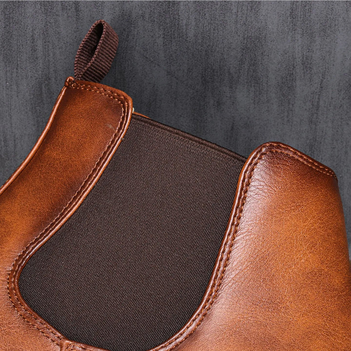 Side view of men's slip-on Chelsea ankle boots, showcasing elastic gussets and sleek profile. Versatile footwear.