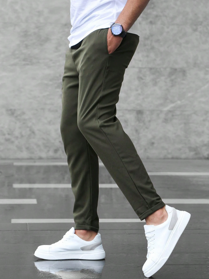 Man wearing versatile slim-fit flexible pants, walking confidently for work or a smart casual outing.