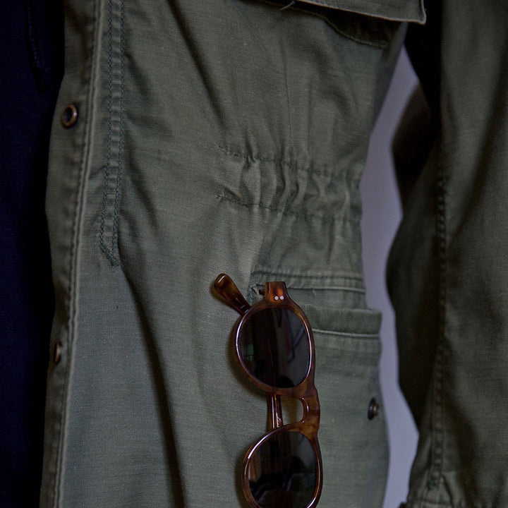 "Men's vintage military jacket with hidden hood, snap-button cargo pockets, wind-resistant, rugged style."