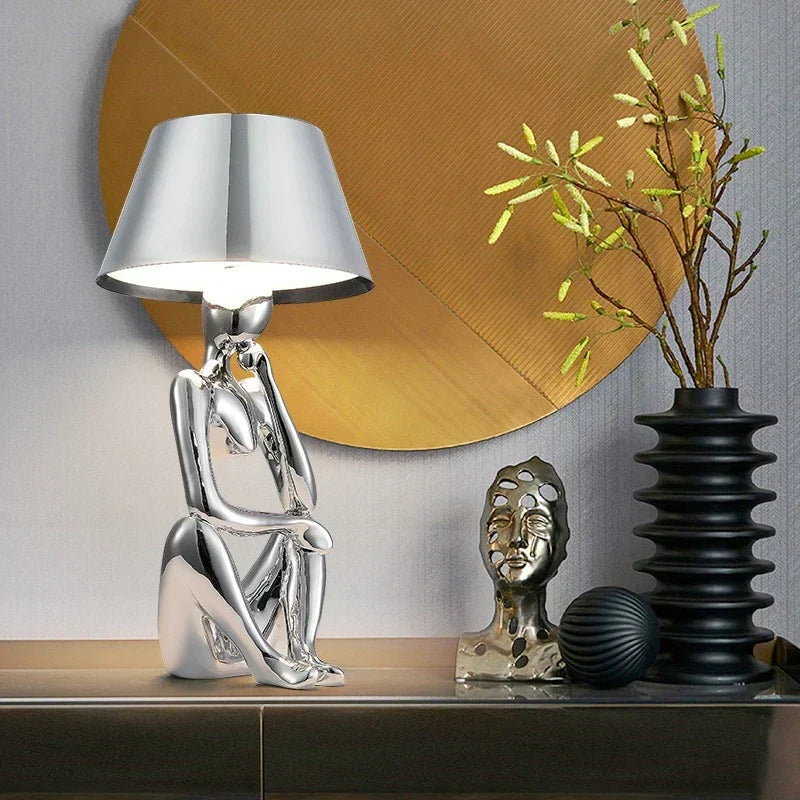 Sleek gold designer table lamp providing elegant ambient lighting. Modern accent for desk, bedroom, or living room decor.