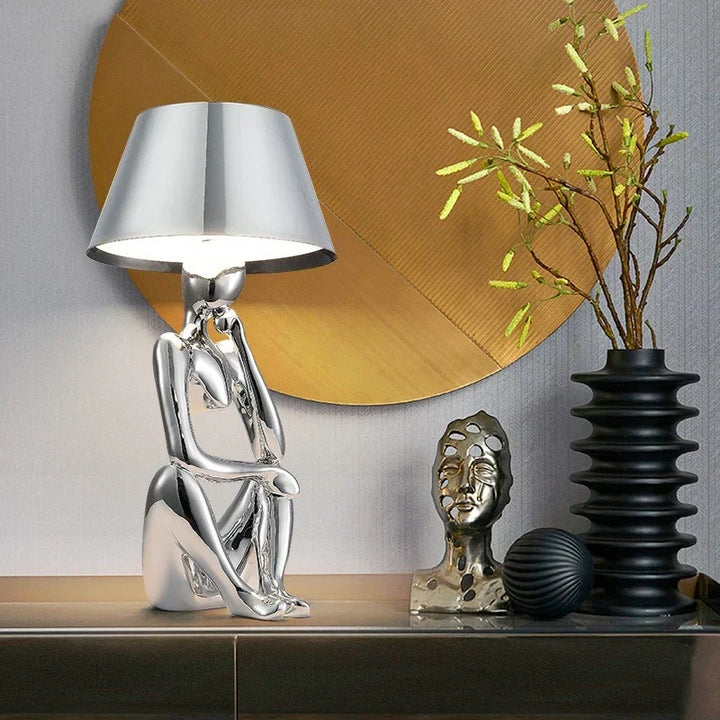 Sleek gold designer table lamp providing elegant ambient lighting. Modern accent for desk, bedroom, or living room decor.