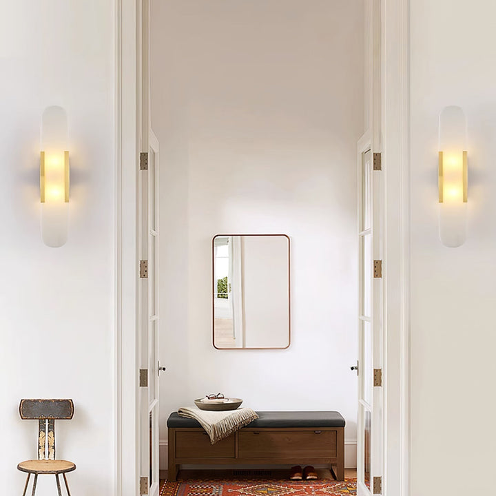 "Modern elongated alabaster wall lamp with metal and brass accents, emits warm glow, suitable for chic interior decor."