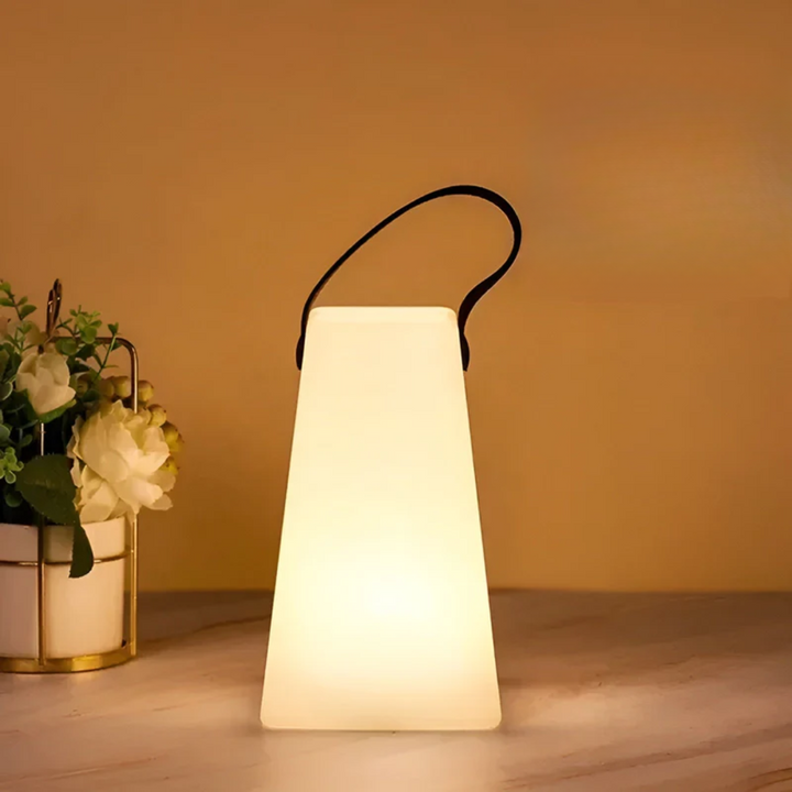 Modern portable wireless LED table lamp, waterproof for indoor ambiance or outdoor patio lighting. Rechargeable design.