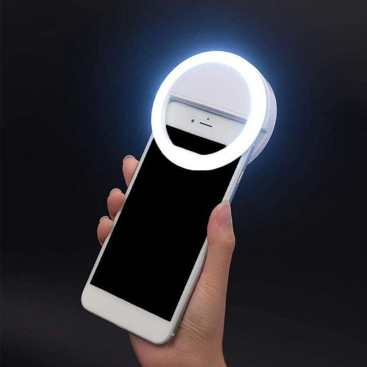 Portable clip-on LED ring light illuminating a smartphone for perfect selfies and videos.