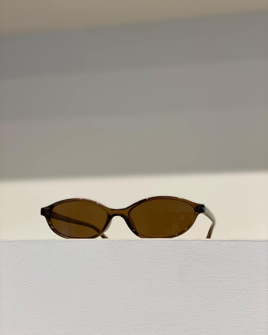 Trendy women's oval sunglasses, evoking 90s style. Available in black, brown, beige; lightweight & sleek.