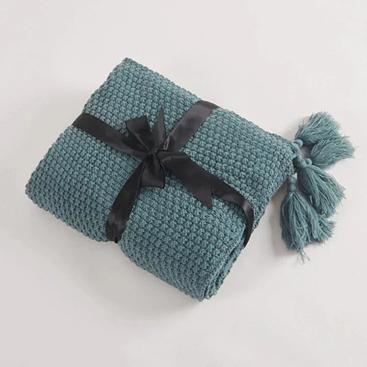Inviting knitted wool blanket with tassels, offering supreme comfort and style as a decorative living room throw.