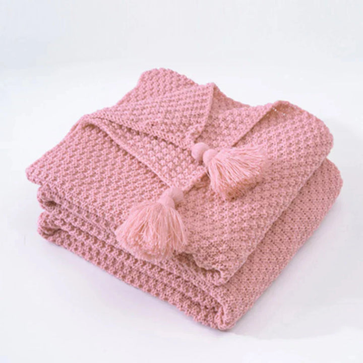 Elegant knitted wool blanket featuring subtle tassels, ideal for bedroom comfort or a chic living room accent.