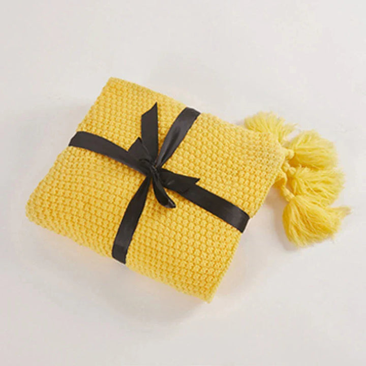 Textured cozy knitted wool blanket with a detailed close-up of its soft fabric and charming tassels.