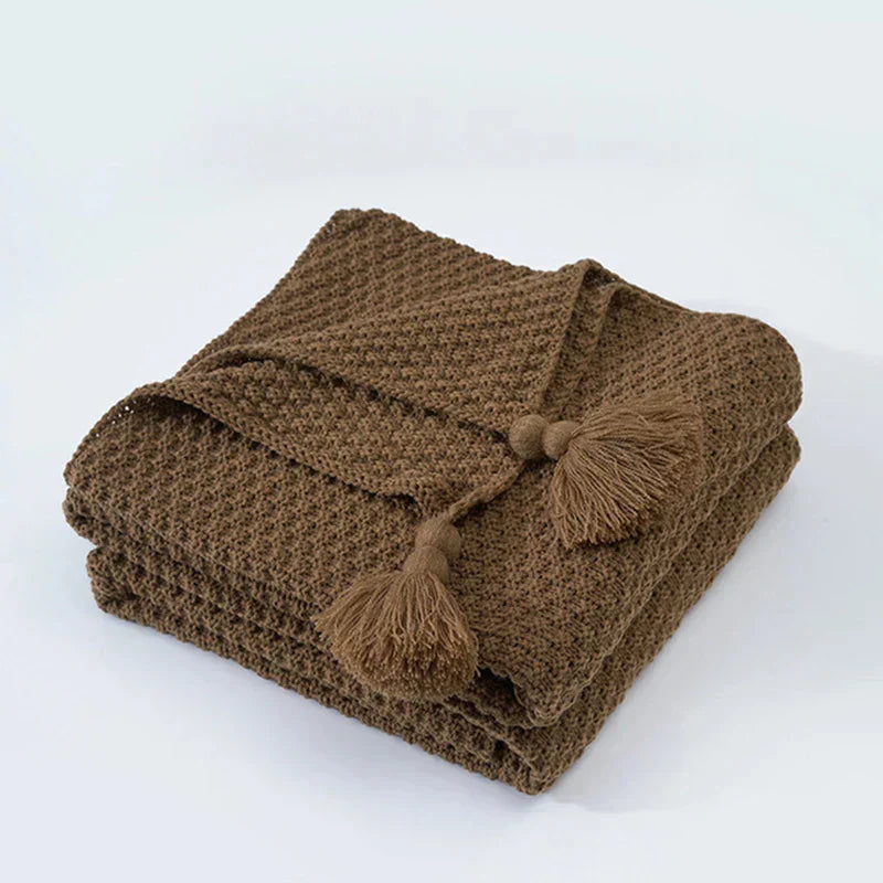 Hand-knitted style wool blanket with tassels, a luxurious and warm home decor accent for cozy evenings.