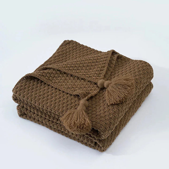 Hand-knitted style wool blanket with tassels, a luxurious and warm home decor accent for cozy evenings.