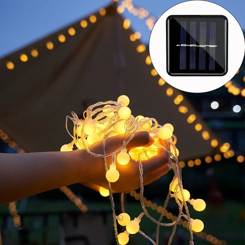 Solar LED festoon string lights illuminating a garden patio, perfect for outdoor decor & parties.