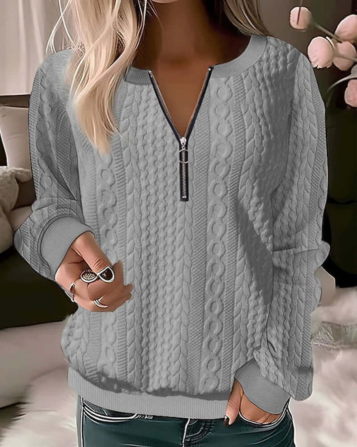Close-up of a white women's knitted half-zip sweater, showing cable knit texture. Perfect for cozy autumn fashion.