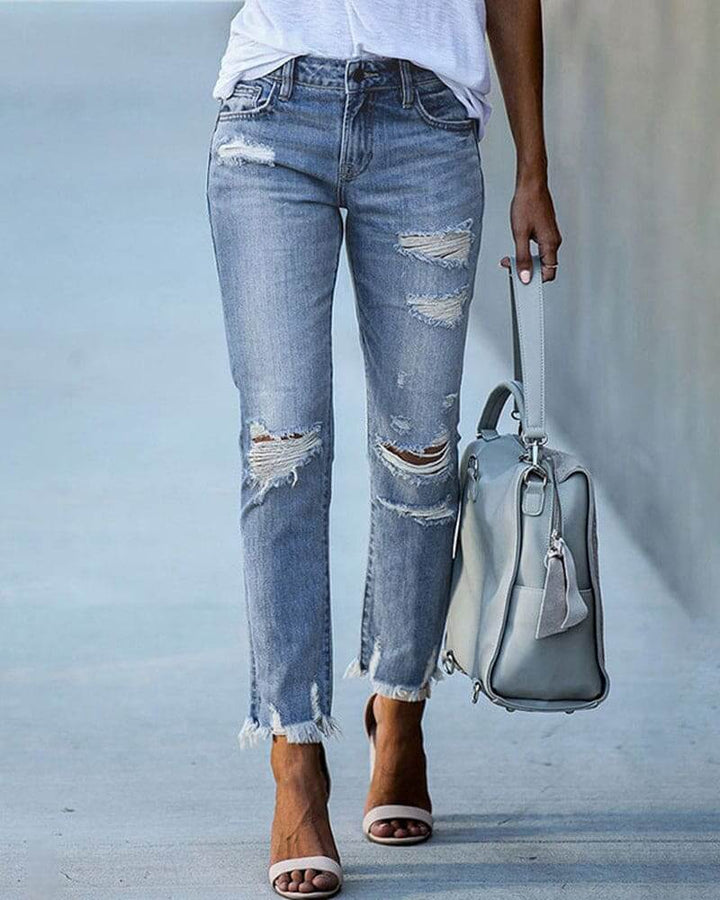 Trendy women's ripped denim jeans in a light blue wash, perfect for a casual fashion look.