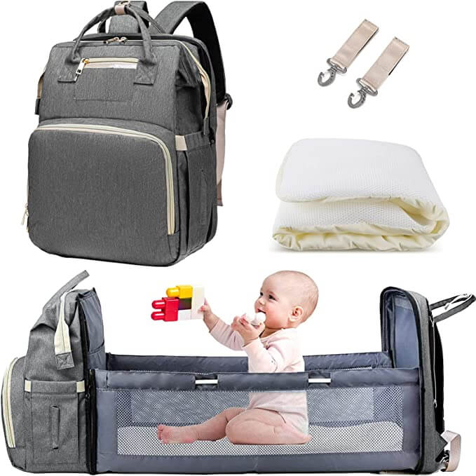 Baby sleeping peacefully in the portable bassinet feature of the multi-pocket diaper travel bag.