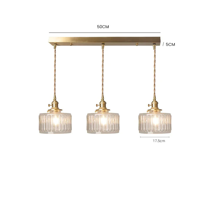 Vintage cylindrical glass pendant lamp casting warm glow; elegant centerpiece for home decor. Perfect for living and dining a