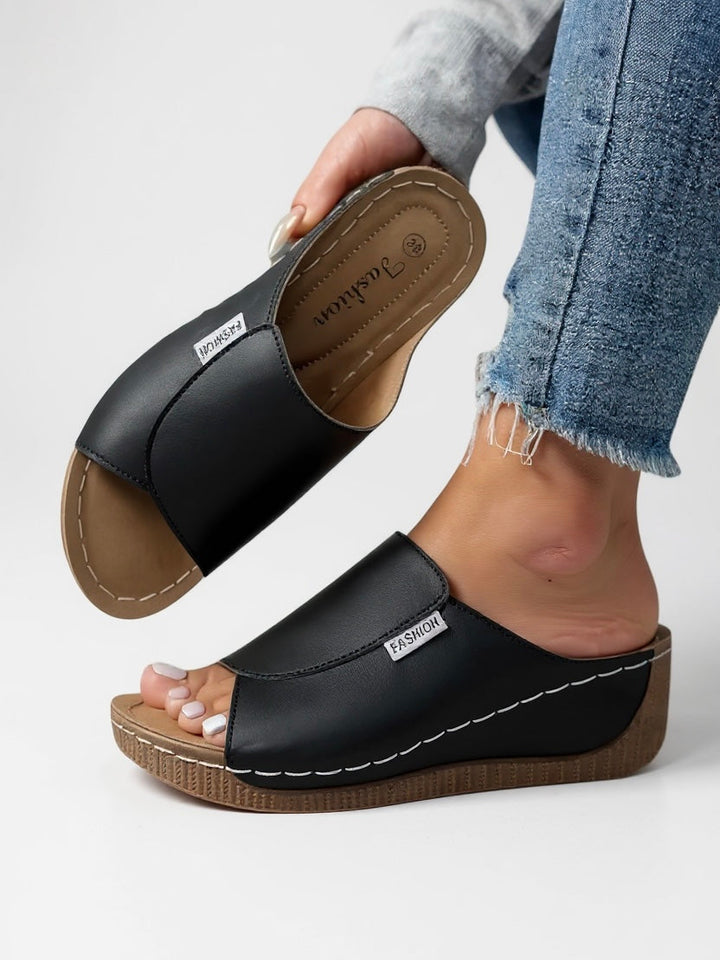 Women's black platform slides offering modern comfort & effortless style.