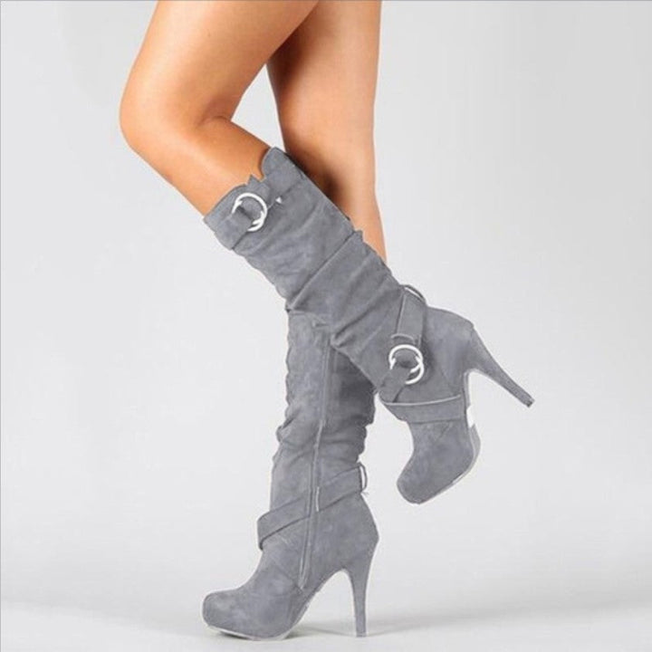 Women's black stiletto knee-high boots with edgy buckle straps, perfect for a bold fashion statement.