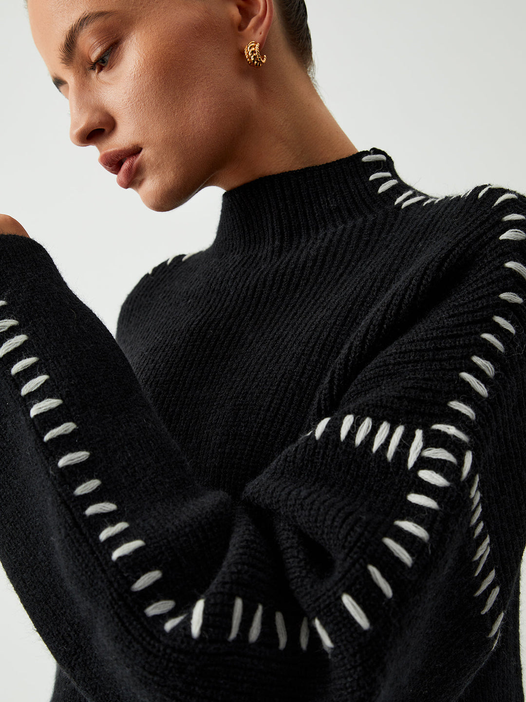 Oversized black mock neck sweater with unique contrast stitching, a chic and relaxed fit for women.